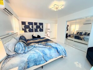 A modern bedroom with a large bed, a mirror, and a wall with abstract art. - Big Groups,Nature View Estates 3 units private pool, WALK TO BEACH (Fort Myers Beach)