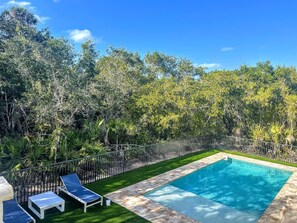 A rectangular swimming pool with a tiled edge, surrounded by a metal fence, and a grassy area with two lounge chairs. - Big Groups,Nature View Estates 3 units private pool, WALK TO BEACH (Fort Myers Beach)