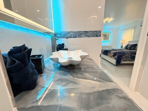 A modern bathroom with a unique sink design, a shower area, and a bedroom with a bed and a nightstand. - Big Groups,Nature View Estates 3 units private pool, WALK TO BEACH (Fort Myers Beach)