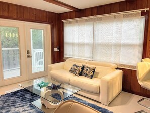A living room with a glass coffee table, a beige sofa with patterned cushions, and a large window with blinds. - Big Groups,Nature View Estates 3 units private pool, WALK TO BEACH (Fort Myers Beach)