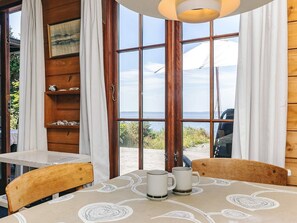 A room with a table, chairs, a view of the sea, and a wooden wall. - 8 Person Holiday Home in Martofte (Martofte)