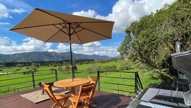 A deck with a grill, a table with chairs, and an umbrella.