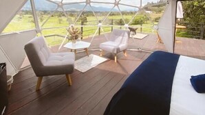 A room with a bed, two chairs, a small table, and a view of the outdoors.