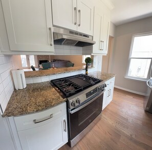 A kitchen with white cabinets, a granite countertop, a stainless steel stove, and an oven. - The Bungalow @ The Battery • Walk to Truist Park & Roxy (Smyrna)