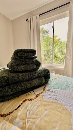 A bed with a patterned blanket and a stack of folded blankets. - The Bungalow @ The Battery • Walk to Truist Park & Roxy (Smyrna)