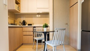 A compact kitchen with a dining table and chairs, a coffee maker, and a potted plant. - Eleuterio Ramirez Apartments by Andes (Santiago)