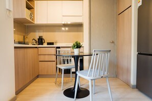 A compact kitchen with a dining table and chairs, a coffee maker, and a potted plant. - Eleuterio Ramirez Apartments by Andes (Santiago)