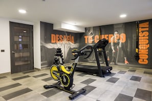 Un gimnasio con una bicicleta estática, una cinta de correr y una pared con mensajes motivacionales.