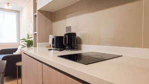 A modern kitchen with a built-in coffee maker, a countertop, and a chair. - Eleuterio Ramirez Apartments by Andes (Santiago)