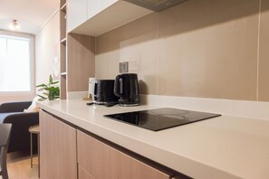 A modern kitchen with a built-in coffee maker, a countertop, and a chair. - Eleuterio Ramirez Apartments by Andes (Santiago)