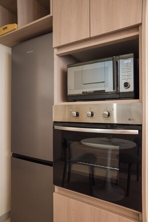 Eine kompakte Küche mit Einbau-Mikrowelle, Backofen und Kühlschrank.