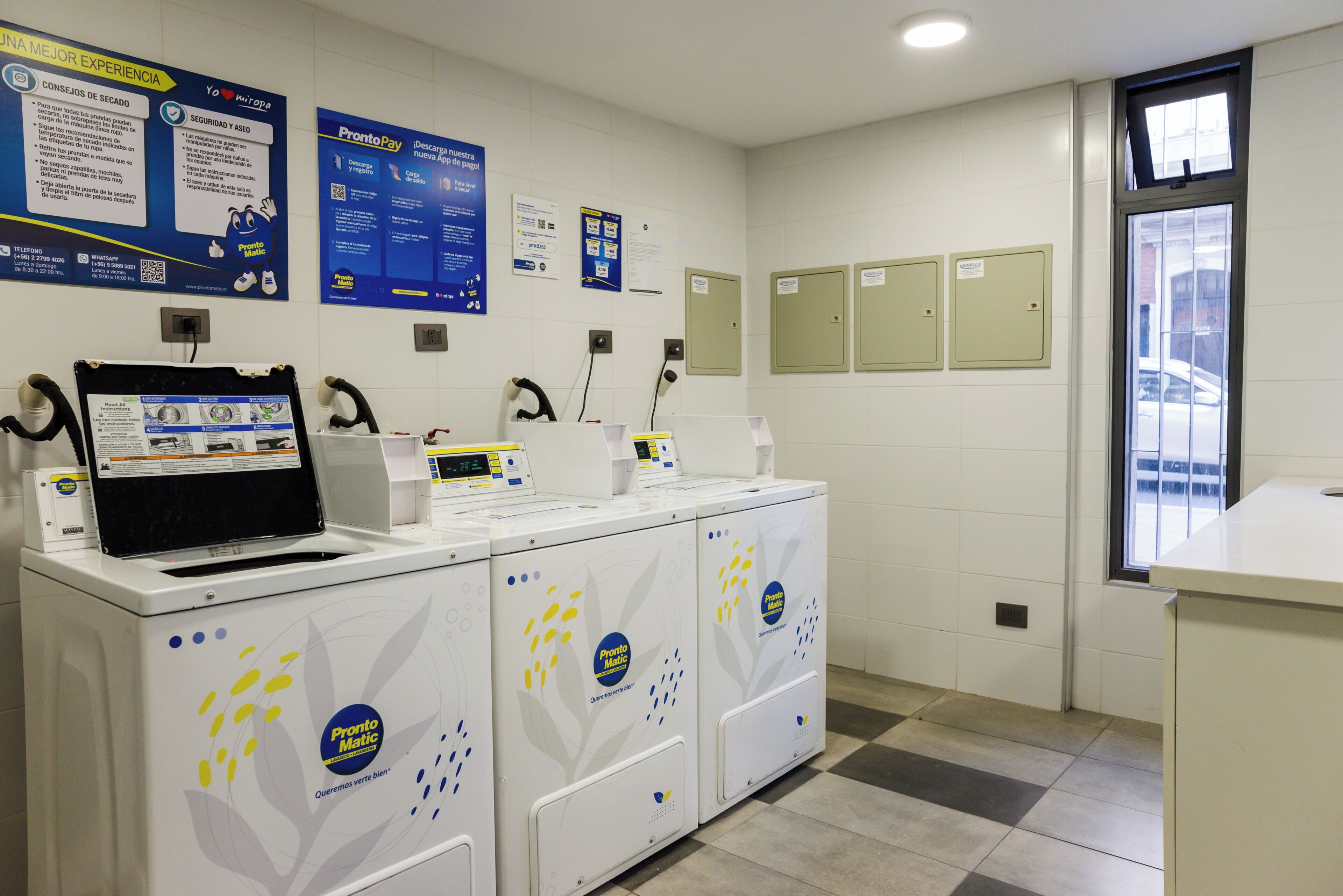 Des toilettes publiques équipées de plusieurs machines à laver, d’un écran d’ordinateur et de panneaux d’information affichés sur les murs.