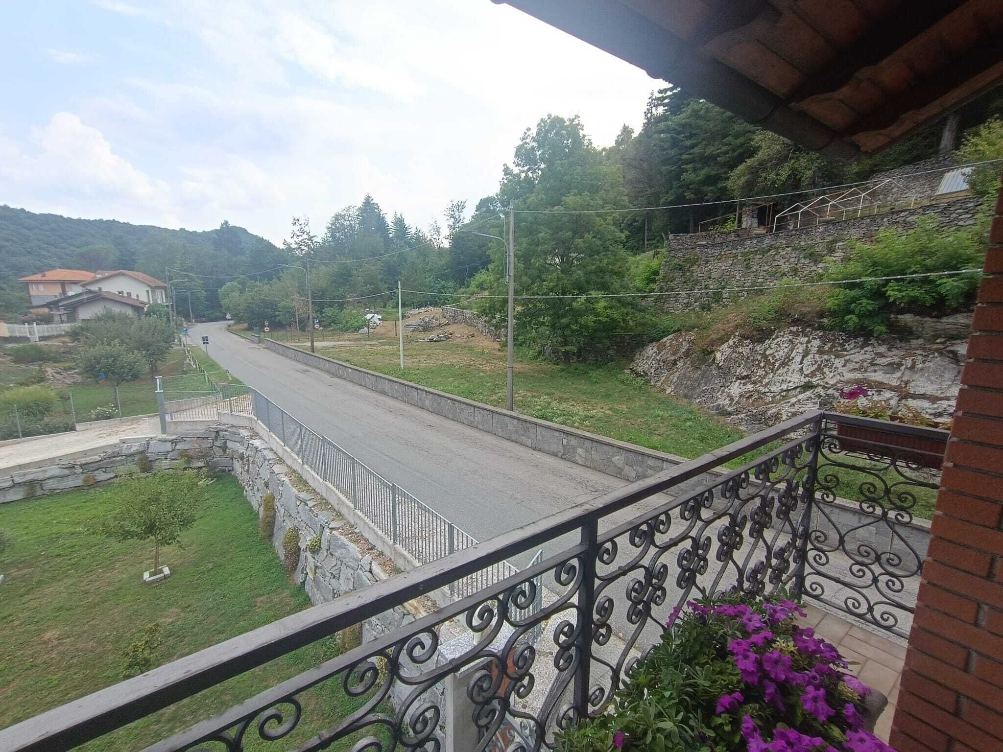 Ein Balkon mit Blick auf eine Straße, Grünflächen und eine Steinmauer.