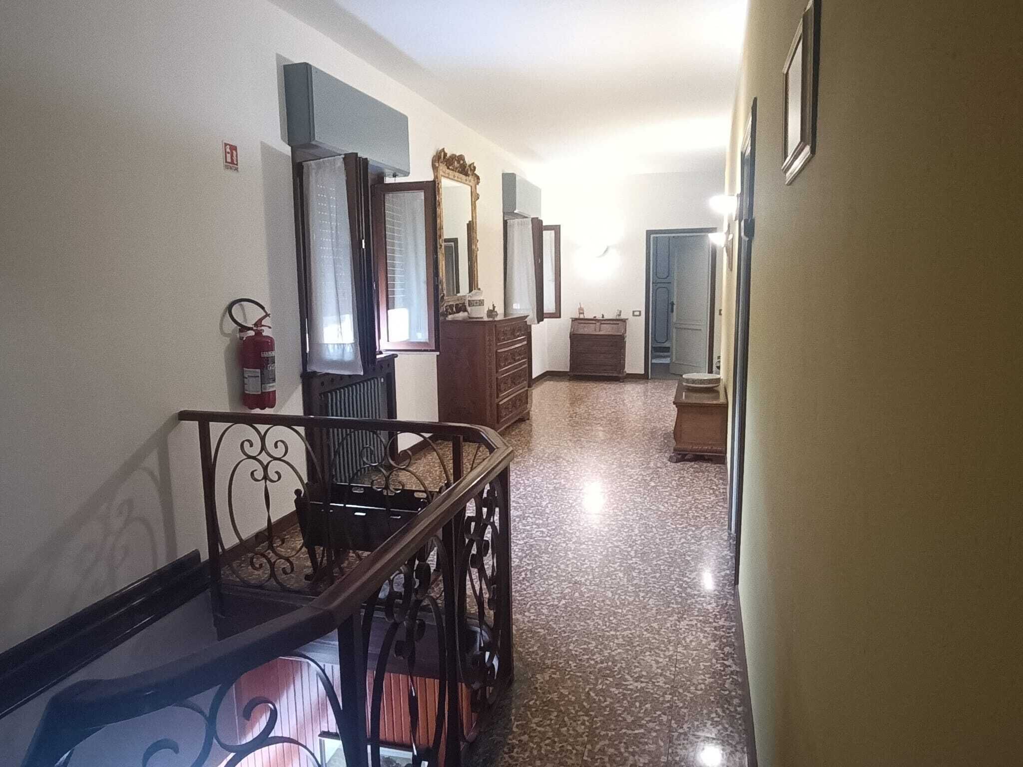 A hallway with a staircase, a fire extinguisher, and a door leading to another room.