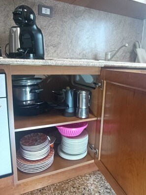 Eine Küche mit Kaffeemaschine, Töpfen und gestapelten Tellern.
