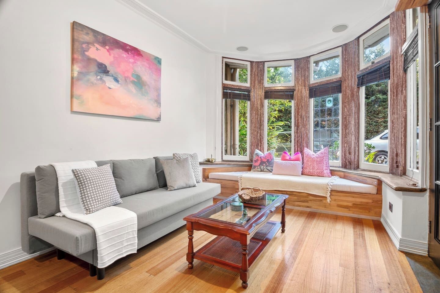 A modern living room with a grey sofa, a coffee table, and a bay window with curtains.