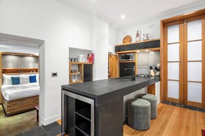 A compact hotel room with a kitchenette, a bed with a headboard, and a sliding door closet. - Rosa and Noir Riverside Escape near Botanic Gardens (South Yarra)