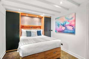 A bedroom with a bed, a headboard, a wall-mounted abstract painting, and a wooden floor. - Rosa and Noir Riverside Escape near Botanic Gardens (South Yarra)