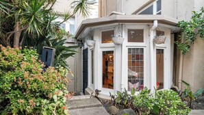 A corner building with a bay window, stone steps, and surrounding greenery. - Rosa and Noir Riverside Escape near Botanic Gardens (South Yarra)