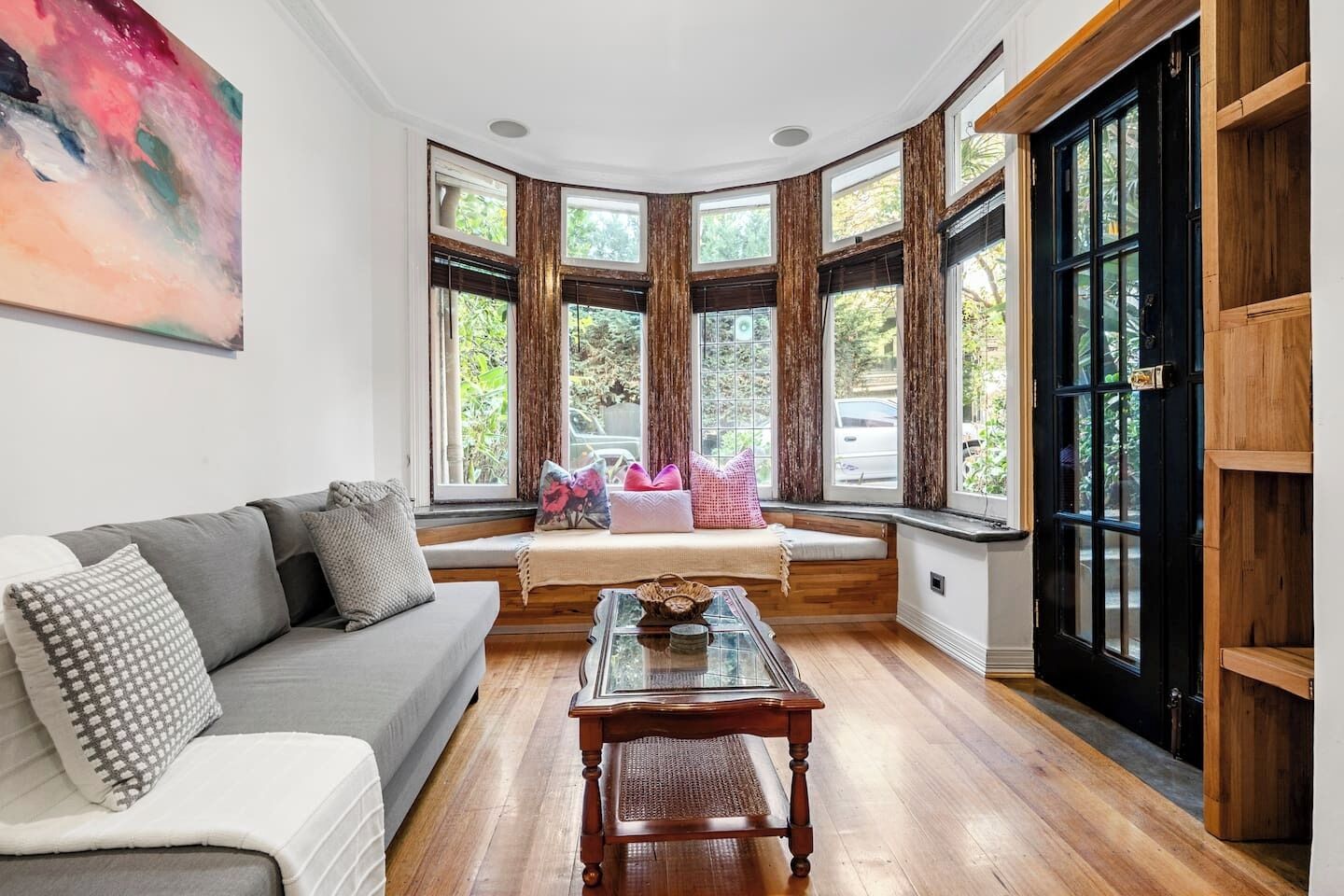 A room with a curved bay window, a sofa, a coffee table, and a bookshelf.