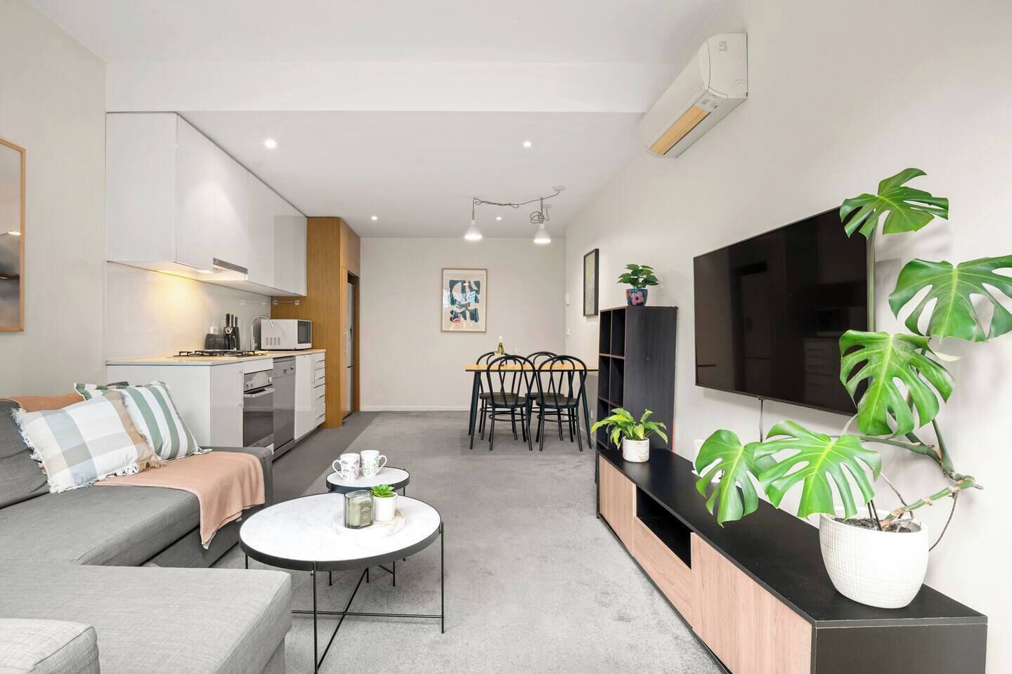Een modern appartement met een woonruimte, kitchenette, eethoek en een grote televisie.