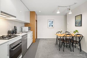 Eine moderne Küche mit Gasherd, Mikrowelle und Kaffeemaschine, sowie ein Essbereich mit Tisch und Stühlen.