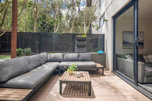 Un espace de vie extérieur moderne, comprenant un canapé modulable, une table basse en bois et une plante en pot.