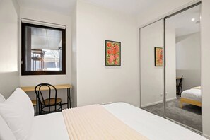 A bedroom with a bed, a desk, a chair, and a sliding door closet. - Richmond Oasis Private Courtyard near MCG and Cafs (Richmond)