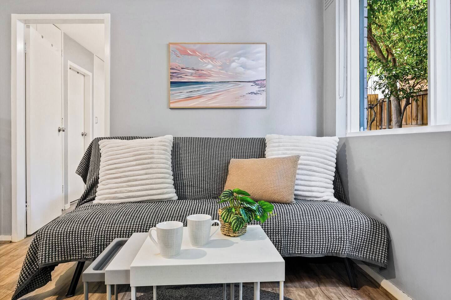 A room with a checkered sofa, a white coffee table, and a painting on the wall.