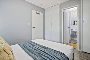 Une chambre à coucher avec un lit, une armoire et une salle de bain visible à travers une porte ouverte.