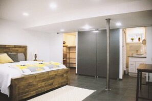 Quarto com cama de madeira, mesa de cabeceira, guarda-roupa e banheiro com pia e espelho.