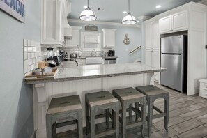 A kitchen with white cabinetry, a granite island, and stainless steel appliances. - Coastal Escape - Beach Access - Pet Friendly (Bolivar Peninsula)