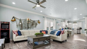 A spacious living room with a sofa, coffee table, and a ceiling fan. - Coastal Escape - Beach Access - Pet Friendly (Bolivar Peninsula)