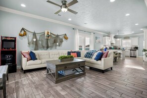 A spacious living room with a sofa, coffee table, and a ceiling fan. - Coastal Escape - Beach Access - Pet Friendly (Bolivar Peninsula)