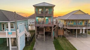 A multi-story building with a balcony on the second floor, a covered front porch, and a small deck area. - Coastal Escape - Beach Access - Pet Friendly (Bolivar Peninsula)