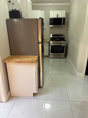 A compact kitchen with a refrigerator, microwave, oven, and a small countertop. - Cozy 1-bedroom house in wonderful Nassau with AC and outdoor fitness area (Nassau)