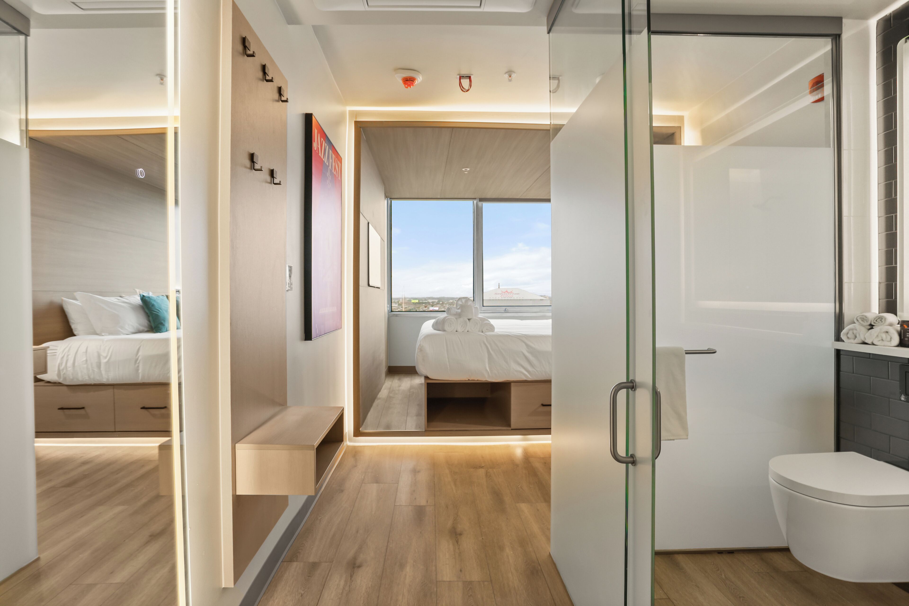 A modern interior with a bed, a bathroom, and a view through a glass door.