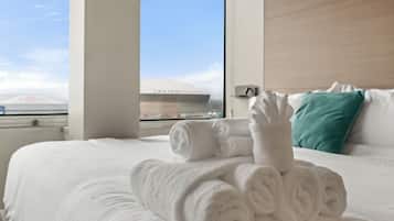 Une chambre d’hôtel avec un lit bien fait, une fenêtre donnant sur un immeuble et un oreiller sur le lit.