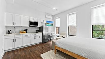 A modern kitchen with white cabinets, a stainless steel refrigerator, and a coffee bar.