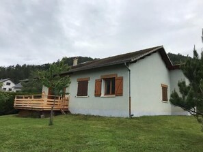 A single-story house with a sloped roof, a wooden deck, and a small tree in the front yard. - Ground floor, terrace, tv, 110m², Pra Loup (Barcelonnette)