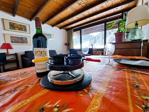 A dining table with a bottle of wine, a panini press, and a glass of water. - 100m from ski slopes, 3rd floor, view ski slopes, balcony, tv, ski locker, 65m², Pra Loup (Pra Loup)