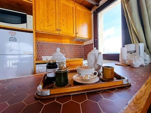 A kitchen with wooden cabinets, a microwave, a refrigerator, and a tray with a teapot, cups, and jars. - 100m from ski slopes, 3rd floor, view ski slopes, balcony, tv, ski locker, 65m², Pra Loup (Pra Loup)