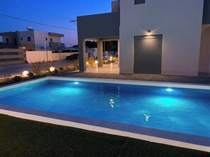 Una piscina con una casa moderna al fondo.