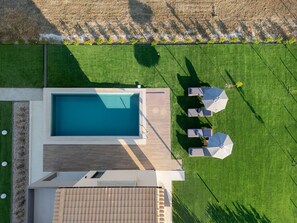 A rooftop pool area with a rectangular pool, adjacent lounge chairs, and a small table.