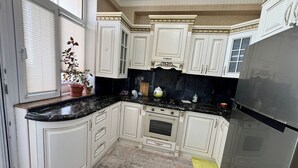 A kitchen with white cabinetry, a black countertop, and a stainless steel refrigerator. - A&P APARTMENT (Bakı)
