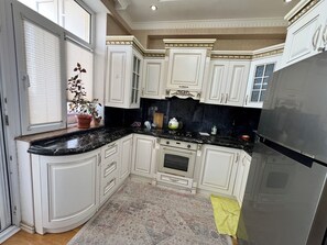 A kitchen with white cabinetry, a black countertop, and a stainless steel refrigerator.