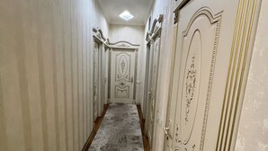 A corridor with ornate wall decorations and a patterned carpet. - A&P APARTMENT (Bakı)