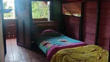 A room with a bed, wooden flooring, and a window.