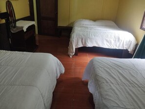 A room with three beds, a wooden chair, and a tiled floor.