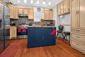 Une cuisine moderne dotée d’un îlot central, d’appareils électroménagers en acier inoxydable et de meubles de rangement en bois.